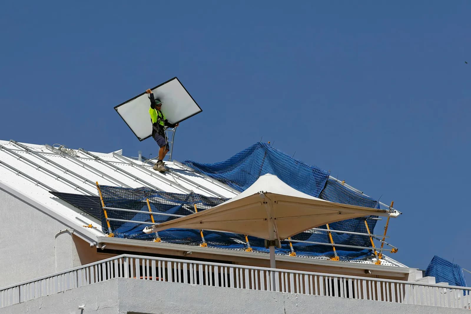 Solar installer carrying a panel across a roof