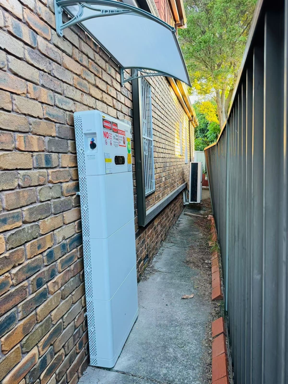 Slimline home battery storage system mounted on the brick wall of a Melbourne home