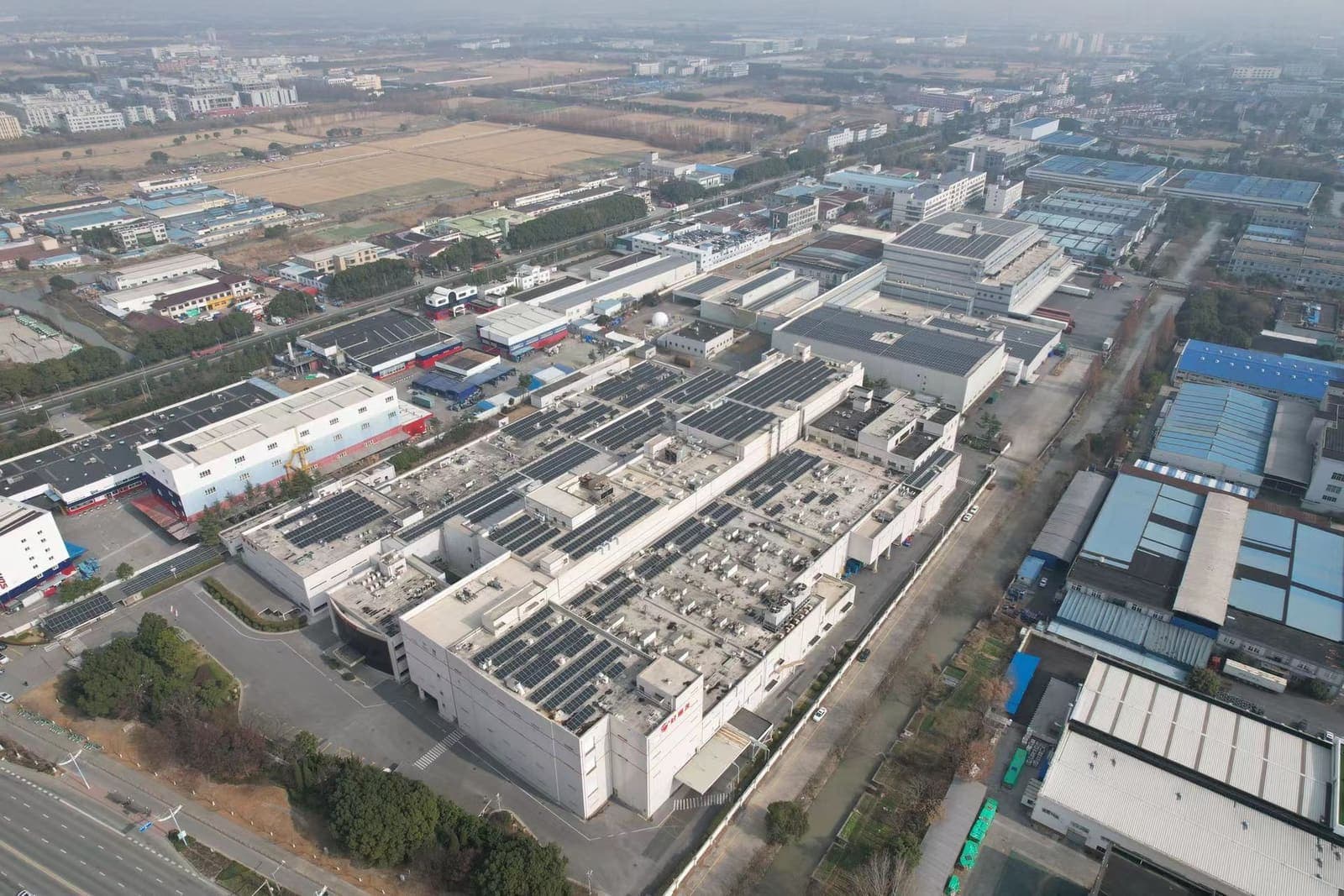 Aerial view of a large manufacturing complex covered with rooftop solar panel arrays